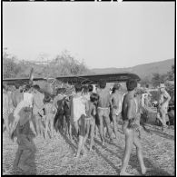 Des villageois Kha attroupés autour d'un avion Morane Saulnier sanitaire.