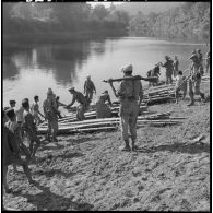 Construction de radeaux pour le transport de paquetages du 2e bataillon de chasseurs laotiens (2e BCL) sur une rivière.