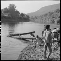 Construction de radeaux pour le transport de paquetages du 2e bataillon de chasseurs laotiens (2e BCL) sur une rivière.