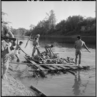 Chargement de paquetages du 2e bataillon de chasseurs laotiens (2e BCL) sur un radeau pour permettre leur franchissement de la rivière.