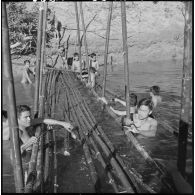 Construction d'un pont de bambous sur la rivière Sé Kampo par des chasseurs du 2e bataillon de chasseurs laotiens et des jeunes garçons.
