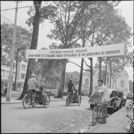 Circulation devant le théâtre de Saigon où une banderole témoigne de manifestations contre le cessez-le-feu et la partage du Vietnam.