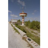 Tour de transmissions au point kilométrique 10 sur l'atoll de Moruroa, et panneau de danger de submersion de la route indiquant "attention, limite de protection du mur, franchissement interdit si feu à éclat en action".