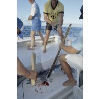 Partie de pêche à la traîne sur une petite vedette en bordure de l'atoll de Moruroa lors d'une visite de membres du gouvernement et d'élus du territoire polynésiens. De nombreux poissons sont attrapés, ici un thazard noir. En arrière-plan, le deuxième adjoint du maire de Papeete, Patrick Bordet.