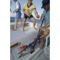 Partie de pêche à la traîne sur une petite vedette en bordure de l'atoll de Moruroa lors d'une visite de membres du gouvernement et d'élus du territoire polynésiens. De nombreux poissons sont attrapés, ici un thazard noir. En arrière-plan, le deuxième adjoint du maire de Papeete, Patrick Bordet.