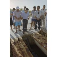 La délégation de membres du gouvernement et d'élus du territoire polynésien, dont Ismaël Tuahu, maire de Taha'a, visite un ancien puits de tir sur l'atoll de Moruroa. Un câble de transmissions affleure au sol.