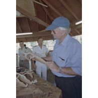 La délégation de membres du gouvernement et d'élus du territoire polynésien visite un atelier d'artisanat tahitien sur l'atoll de Moruroa. Gaston Flosse, président de la Polynésie française, examine des pirogues miniatures.