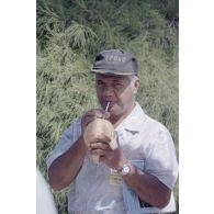 Un membre de la délégation évangélique, padré tahitien, déguste une noix de coco lors de la visite du gouvernement et d'élus du territoire polynésien sur l'atoll de Moruroa.