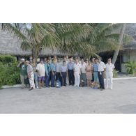 Photographie de groupe de la délégation de membres du gouvernement et d'élus du territoire polynésien avant son départ de l'atoll de Moruroa. Gaston Flosse, président de la Polynésie française (chemisette bleue), Ismaël Tuahu, maire de Taha'a, le maire adjoint de Papeete, Eugène Bessert, maire de Papara (casquette bleue), et le colonel Patrick Delcourt, commandant le site (COMSITE), sont présents.