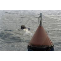 Un plongeur du service mixte de surveillance radiologique et biologique (SMSRB) plonge à côté de la bouée du précédent tir d'expérimentation nucléaire sous lagon Lycurgue du 15 juillet 1991 en mer dans les eaux de Moruroa.