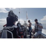 Départ à bord d'un canot du service mixte de surveillance radiologique et biologique (SMSRB) pour une séance de plongée sous-marine de Jean-Jacques de Peretti, ministre de l'Outre-mer, avec Benoit Dufeutrelle, caméraman, et Hervé Keraval, preneur de son, de l'équipe de tournage de l'ECPA, dans le lagon de l'atoll de Moruroa.