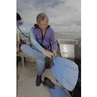 Jean-Jacques de Peretti, ministre de l'Outre-mer, s'équipe de palmes avant une plongée sous-marine, à bord d'un canot du groupe de prélèvements biologiques du service mixte de surveillance radiologique et biologique (SMSRB) dans le lagon de l'atoll de Moruroa.