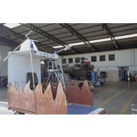 Montage d'un hélicoptère Puma SA-330 dans un hangar de l’escadron de transport d’outre-mer (ETOM) 82 de Moruroa. Au premier plan, un chariot du commandement du transport aérien (COTAM).
