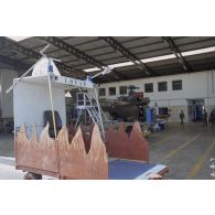 Montage d'un hélicoptère Puma SA-330 dans un hangar de l’escadron de transport d’outre-mer (ETOM) 82 de Moruroa. Au premier plan, un chariot du commandement du transport aérien (COTAM).