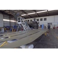 Montage d'un hélicoptère Puma SA-330 dans un hangar de l’escadron de transport d’outre-mer (ETOM) 82 de Moruroa. Un mécanicien s'affaire sur les pales.
