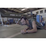 Montage d'un hélicoptère Puma SA-330 dans un hangar de l’escadron de transport d’outre-mer (ETOM) 82 de Moruroa. Un mécanicien s'affaire sur les pales.