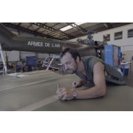 Montage d'un hélicoptère Puma SA-330 dans un hangar de l’escadron de transport d’outre-mer (ETOM) 82 de Moruroa. Un mécanicien s'affaire sur les pales.