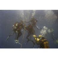 Vue sous-marine pendant la plongée de Jean-Jacques de Peretti, ministre de l'Outre-mer, et de Marine Jacquemin, journaliste de la télévision TF1, avec un caméraman de TF1 et l'adjudant Patrick Robaston,caméraman de l'ECPA dans la zone d'un puits de tir d'expérimentation nucléaire sous lagon.