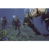 Vue sous-marine pendant la plongée de Jean-Jacques de Peretti, ministre de l'Outre-mer, et de Marine Jacquemin, journaliste de la télévision TF1, avec un caméraman de TF1, dans la zone d'un puits de tir d'expérimentation nucléaire sous lagon.