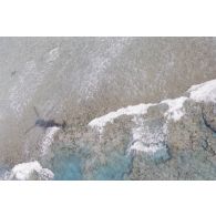 Vue aérienne du platier côté océan une heure après le troisième tir souterrain Aepytos du 27 octobre 1995 lors de la dernière campagne d'essais nucléaires dans le lagon de l'atoll de Moruroa. Ombre de l'hélicoptère.