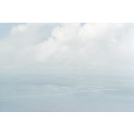 Vue aérienne de l'onde de choc et de la barge d'enregistrement et de mesure du commissariat à l'énergie atomique (CEA) sur la zone du cinquième tir Thémisto de la dernière série des essais nucléaires français dans le lagon de l'atoll de Moruroa, prise depuis l'hélicoptère Cigogne. Le lagon blanc est couvert de nuages.