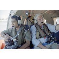 Portrait de membres de l'équipe de tournage de l'ECPA, l'adjudant Patrick Babef, caméraman, et Jean Valmont, réalisateur, à bord de l'hélicoptère Cigogne, après le cinquième tir Thémisto de la dernière série des essais nucléaires français dans le lagon de l'atoll de Moruroa.