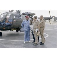 A l'héliport en zone aéroportuaire de l'atoll de Moruroa, Charles Hernu, ministre de la Défense, discute avec le général de corps d’armée aérienne Michel Rouyer, directeur des centres d'expérimentations nucléaires (DIRCEN) et des membres de sa délégation, devant un hélicoptère de reconnaissance Alouette III.