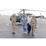 A l'héliport en zone aéroportuaire de l'atoll de Moruroa, Charles Hernu, ministre de la Défense, discute avec le général de corps d’armée aérienne Michel Rouyer, directeur des centres d'expérimentations nucléaires (DIRCEN) et des membres de sa délégation, devant un hélicoptère de reconnaissance Alouette III.