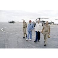 A l'héliport en zone aéroportuaire de l'atoll de Moruroa, Charles Hernu, ministre de la Défense, discute avec le général de corps d’armée aérienne Michel Rouyer, directeur des centres d'expérimentations nucléaires (DIRCEN) et des membres de sa délégation, devant un hélicoptère de reconnaissance Alouette III.