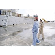 Visite de la zone portuaire sur l'atoll de Moruroa. Charles Hernu, ministre de la Défense, et le général de corps d’armée aérienne Michel Rouyer, directeur des centres d'expérimentations nucléaires (DIRCEN), devant le bâtiment de débarquement de chars (BDC) Trieux (L9007) à quai.