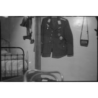 La veste d'uniforme du reporter Robert Schiffmann avec sur la gauche, la casquette, sa ceinture ainsi que deux boîtiers photographiques Leica enveloppés dans une pochette de cuir.