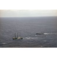 Vue aérienne du navire Rainbow Warrior II de l'association Greenpeace après son arraisonnement escorté par le patrouilleur La Tapageuse (P691) et cinq zodiacs, à proximité de l'atoll de Morurua.