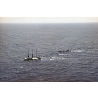 Vue aérienne du navire Rainbow Warrior II de l'association Greenpeace après son arraisonnement escorté par le patrouilleur La Tapageuse (P691) et cinq zodiacs, à proximité de l'atoll de Morurua.