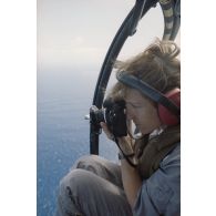 Le maître Fabienne Seynat, photographe de l’ECPA, réalise une prise de vue aérienne à bord d'un hélicoptère.