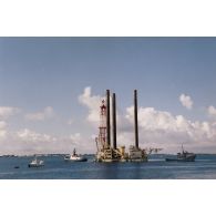 Zone portuaire de Moruroa : la plateforme de forage Tila du commissariat à l'énergie atomique (CEA) entourée de remorqueurs, dont le remorqueur portuaire et côtier Maroa (A637).