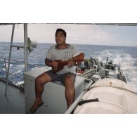 Un matelot polynésien musicien joue du ukulélé à bord du patrouilleur La Railleuse (P689).