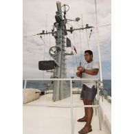 Un matelot polynésien musicien joue du ukulélé à bord du patrouilleur La Railleuse (P689).