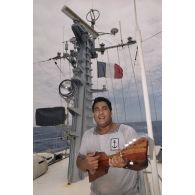Un matelot polynésien musicien joue du ukulélé à bord du patrouilleur La Railleuse (P689).