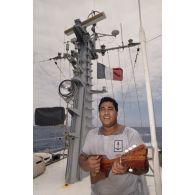 Un matelot polynésien musicien joue du ukulélé à bord du patrouilleur La Railleuse (P689).