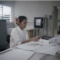 Portrait d'une laborantine participant au contrôle de la contamination d'éléments nutritifs au centre de contrôle biologique du centre technique (CT) de Mahina (Tahiti). Des aliments prélevés réduits en cendre sont contrôlés sous forme de pastille d'agglomérés calcinés.