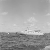 Préparatifs et mise en place des matériels pour le tir d'essai nucléaire Licorne du 3 juillet 1970 à Moruroa (Mururoa). Ballon captif en vol en arrière-plan de la vedette de transport de personnel (VTP 41) qui assure la liaison avec la zone Dindon.