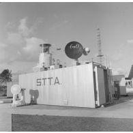 Préparatifs et mise en place des matériels pour le tir d'essai nucléaire Licorne du 3 juillet 1970 à Moruroa (Mururoa). Appareils du Centre d'expérimentations du Pacifique (CEP) sur le toit d'un container portant l'inscription "STTA" et antennes sur l'atoll de Moruroa.