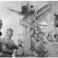 Visite des installations à bord du croiseur de commandement De Grasse lors du tir Licorne du 3 juillet 1970 de Michel Debré, ministre de la Défense, et de la délégation. Exposé sur le pont au groupe muni de lunettes de protection.