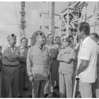 Visite des installations à bord du croiseur de commandement De Grasse lors du tir Licorne du 3 juillet 1970 de Michel Debré, ministre de la Défense, et de la délégation. Exposé sur le pont au groupe muni de lunettes de protection.