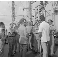 Visite des installations à bord du croiseur de commandement De Grasse lors du tir Licorne du 3 juillet 1970 de Michel Debré, ministre de la Défense, et de la délégation. Exposé sur le pont au groupe muni de lunettes de protection.