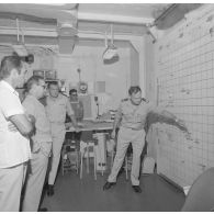 H5. Visite des installations à bord du croiseur de commandement De Grasse de Michel Debré, ministre de la Défense, lors du tir Licorne du 3 juillet 1970. Exposé devant une carte de l'atoll de Moruroa (Mururoa).