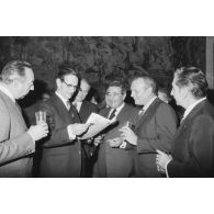 Robert Galley, ministre des Armées, donne un cocktail en l'honneur des journalistes spécialisés ayant participé au voyage en Polynésie française, et reçoit leurs voeux dans les salons de l'hôtel de Brienne. Consultation d'un journal.