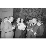 Robert Galley, ministre des Armées, donne un cocktail en l'honneur des journalistes spécialisés ayant participé au voyage en Polynésie française, et reçoit leurs voeux dans les salons de l'hôtel de Brienne. Consultation d'un journal.