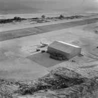 Vue aérienne d'installations et infrastructures sur un atoll. Aéroport. Avion Piper PA-23 Aztec du groupe aérien mixte (GAM) 82 au ravitaillement. Peut-être sur l'atoll d'Hao.