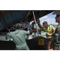 Des soldats du détachement de transit interarmées (DéTIA) aident des convoyeurs espagnols à charger du fret à bord d'un avion Hercules C-130 sur l'aéroport de Bamako-Sénou, au Mali.